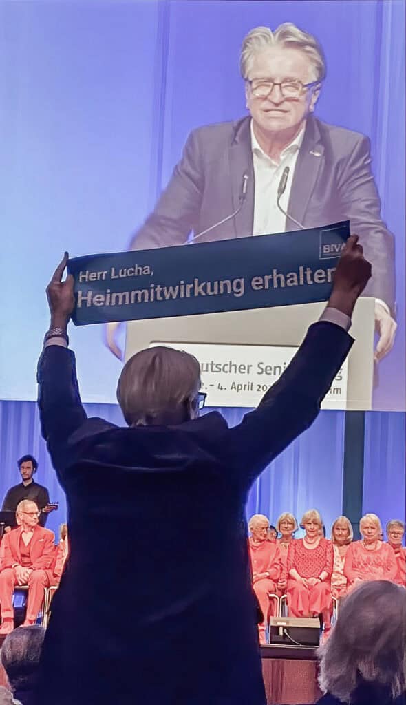 Protest mit Banner bei der Rede Ministers Lucha