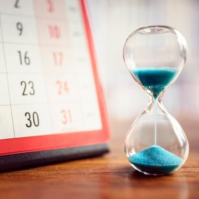 Kalender und Sanduhr mit blauem Sand